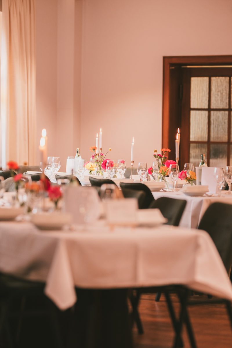 Gedeckte Tische im Saal vor einer weißen Flügeltür