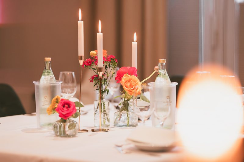 Tischdekoration aus Kerzen und kleinen Blumenvasen