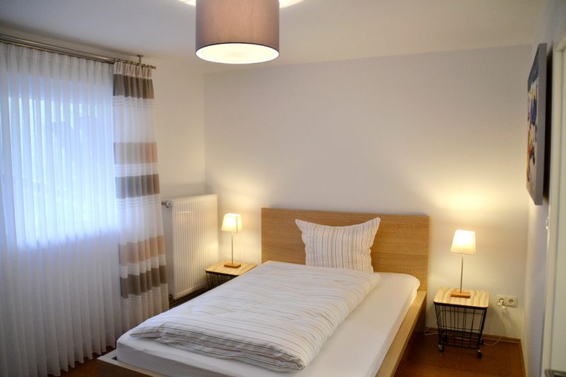 Zimmer mit Bett und heller Holzeinrichtung